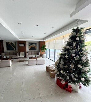 Ein modernes Wohnzimmer mit einem großen Weihnachtsbaum, Sofas und einem großen Fenster.