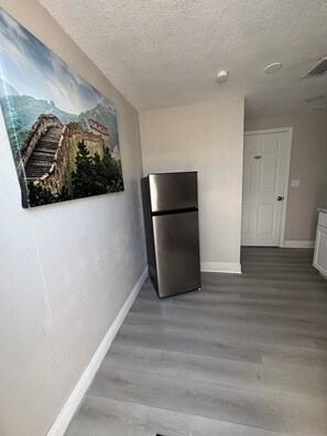 A kitchen with a stainless steel refrigerator, a white door, and a wooden floor. - Home Away From Home – Holiday, FL (Holiday)