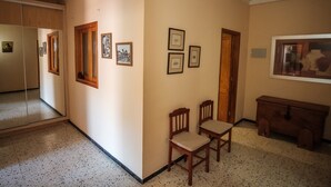 Un pasillo con espejo, puertas de madera, cuadros enmarcados y un banco.