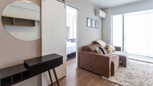 Un dormitorio moderno con cama, sofá, escritorio, espejo y ventana grande.