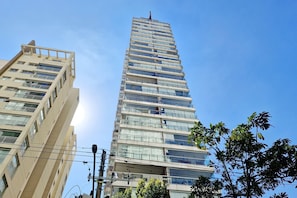 Un immeuble de grande hauteur, avec de nombreux étages, de grandes fenêtres et un ciel dégagé.