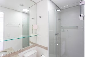 Une salle de bain moderne avec une douche à parois de verre, une étagère en verre au-dessus du lavabo et des toilettes.