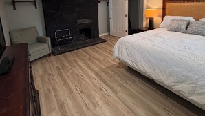 Ein Schlafzimmer mit Bett, Kamin, Sofa und Holzboden.