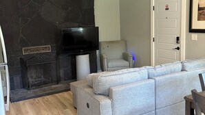 Ein Wohnzimmer mit Kamin, einer Couch, einem Fernseher und einer Tür mit einem Rauchverbot-Schild.