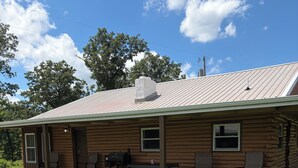 Eine Holzhütte mit Veranda, Sitzgelegenheit im Freien und einem Feuerkorb.