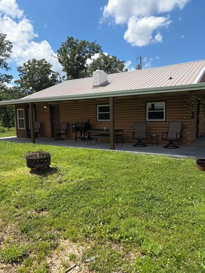 Eine Holzhütte mit Veranda, Sitzgelegenheit im Freien und einem Feuerkorb.