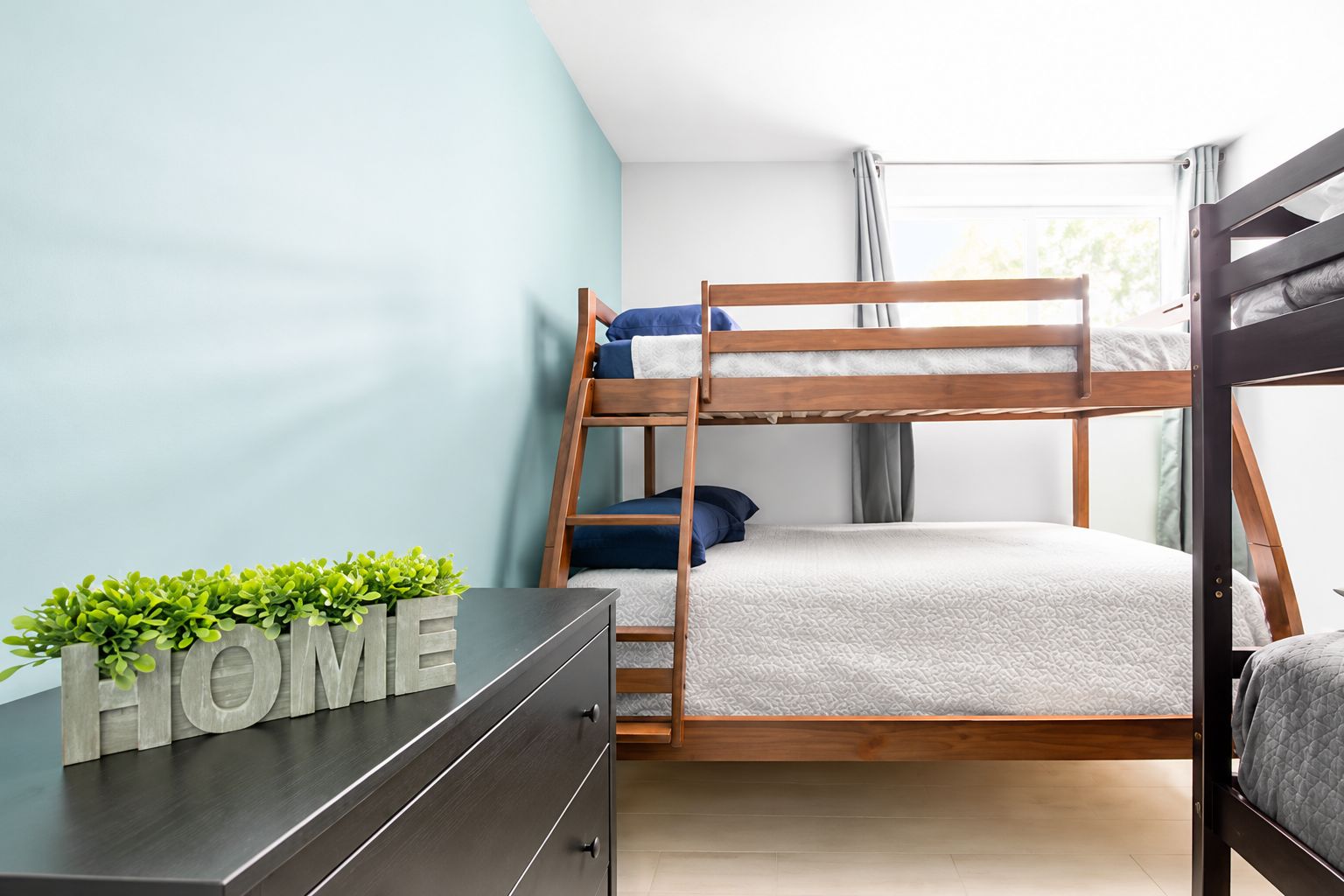 Un lit superposé dans une chambre qui contient une commode et une plante.