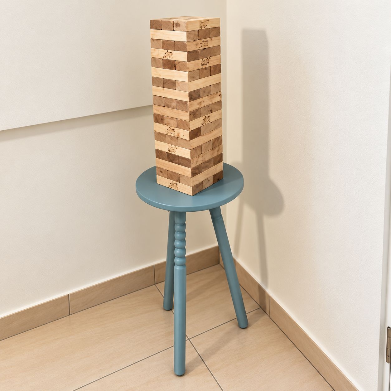 A wooden block structure on a blue stool against a white wall.
