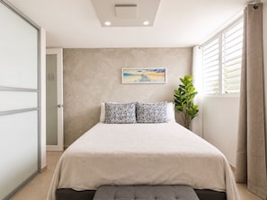 Ein Schlafzimmer mit einem Bett, einem Gemälde, einer Pflanze und einem Fenster mit Vorhängen.