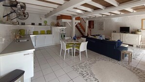 Amplia sala de estar con cocina, mesa de comedor y sofá azul.