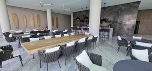 Ein geräumiger Essbereich mit einem langen Holztisch, umgeben von Stühlen, einer Bar und einem modernen Interieur.