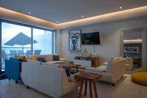 Ein modernes Wohnzimmer mit einer Sofagarnitur, einem Couchtisch und einem an der Wand montierten Fernseher.