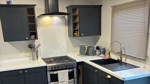 Una cocina compacta con armarios oscuros, estufa a gas, horno empotrado y un lavamanos.