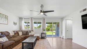 Un salon avec un canapé en cuir marron, une table basse en bois et un ventilateur de plafond.