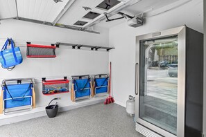 A clean, well-organized room with storage racks, a bucket, and a large window. - Emerald Hideout (Miramar Beach)
