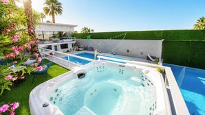Ein Garten mit Schwimmbad, Whirlpool und Sitzbereich im Freien.