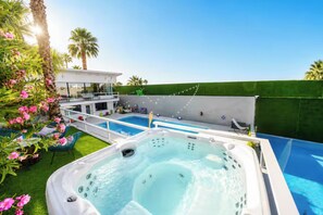 Ein Garten mit Schwimmbad, Whirlpool und Sitzbereich im Freien.