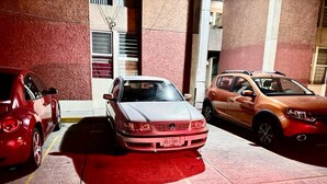 Un área de estacionamiento con tres coches aparcados en fila.