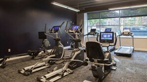 Un gimnasio con bicicletas estáticas, cintas de correr y una máquina de remo.