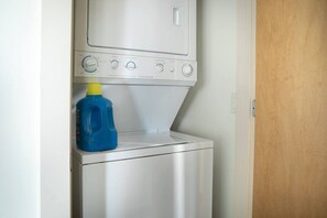 Una unidad compacta de lavadora y secadora con una botella de detergente azul encima.