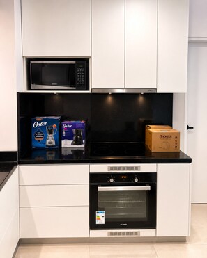 Eine moderne Küche mit Mikrowelle, Kaffeemaschine und Toaster auf der Arbeitsplatte, darunter ein Bosch-Ofen.