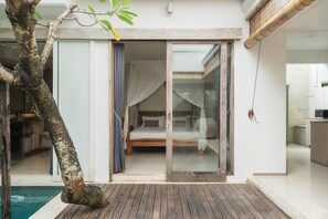 Ein Schlafzimmer mit Bett, einer Schiebetür und Blick auf einen Pool.