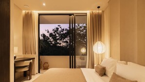 Ein Schlafzimmer mit einem großen Bett, einem Schreibtisch und Blick durch eine Schiebetür.