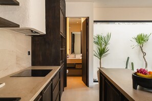 Eine moderne Küche mit dunklen Schränken, einer Marmorarbeitsplatte und Blick ins angrenzende Badezimmer.