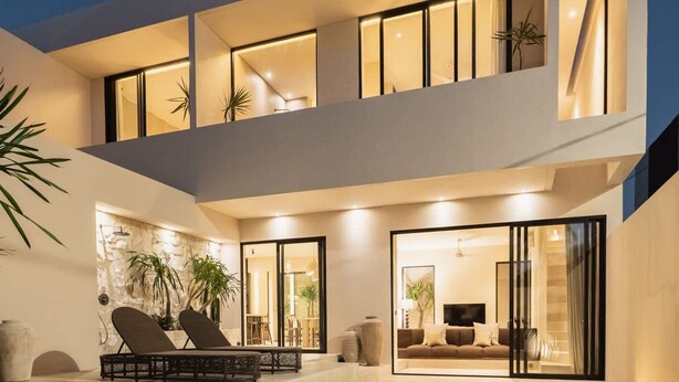 Ein modernes Haus mit Swimmingpool, einem Balkon mit Sitzgelegenheit und einem hellen Innenraum.