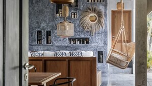 A modern interior with a wooden dining table, a bench with patterned cushions, and a hanging wicker chair. - Architectural 2 bedroom Pool Villa Berawa (Kecamatan Kuta Utara)