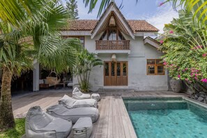 Ein Haus mit Pool, Holzterrasse und Liegestühlen.