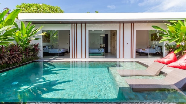 A modern building with a swimming pool, lounge area, and a glass door entrance. - Cozy 3BR Villa w  Private Pool near Berawa Beach (Kecamatan Kuta Utara)