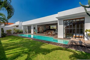 A modern house with a swimming pool, outdoor seating, and a well-maintained lawn. - Loft Style Villa with Pool and Ricefield View (Seminyak)