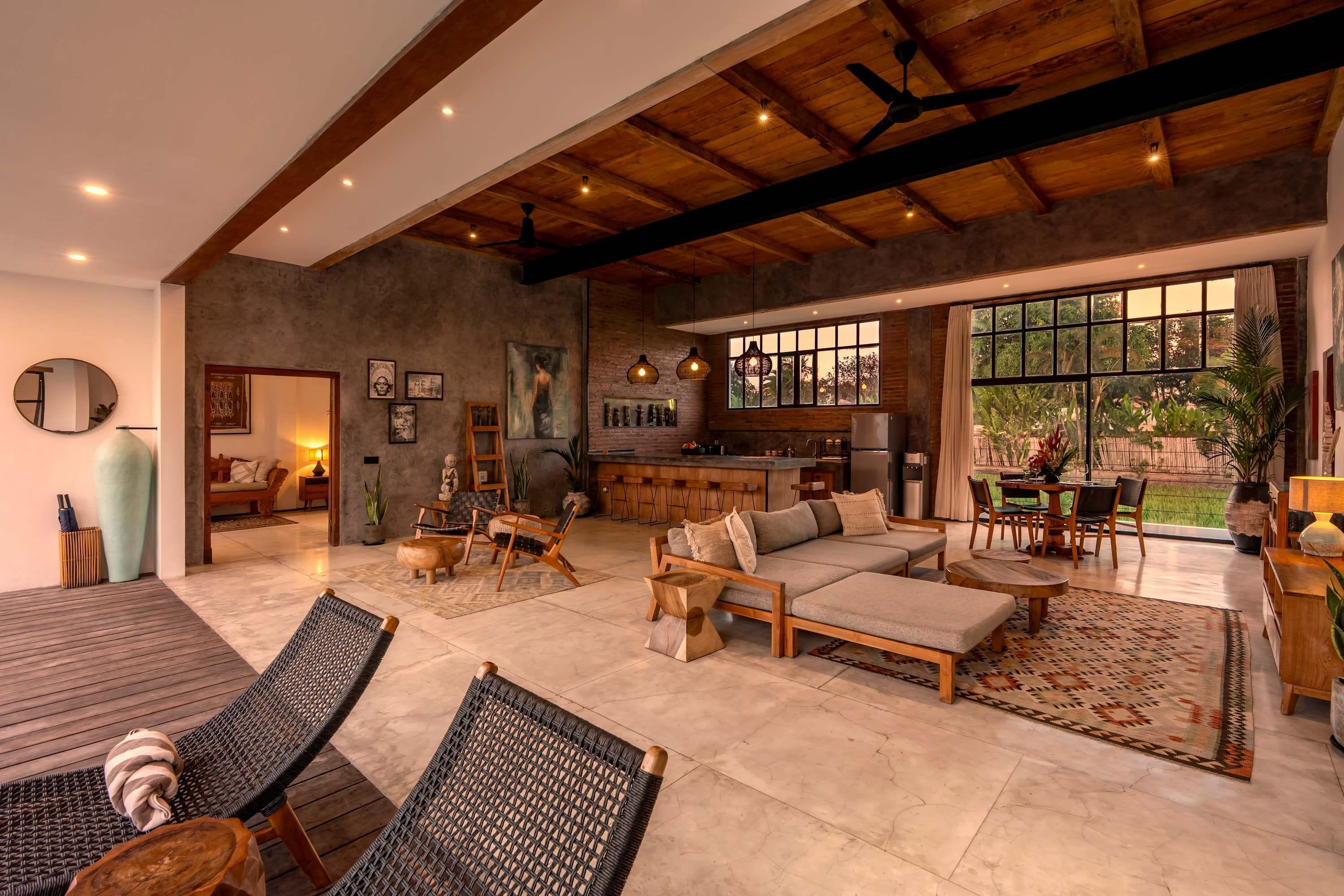 Amplia sala de estar con cocina, comedor y un ventanal con vistas al exterior.