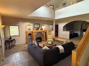 A spacious living area with a fireplace, a staircase, and a second-floor balcony. - Blue River Retreat - Private Hot Tub & Mtn Views (Blue River)