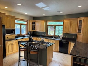 A kitchen with wooden cabinets, a central island, a stove, and a dishwasher. - Blue River Retreat - Private Hot Tub & Mtn Views (Blue River)