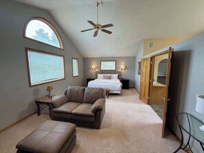 A bedroom with a bed, a sofa, a ceiling fan, and a large window. - Blue River Retreat - Private Hot Tub & Mtn Views (Blue River)