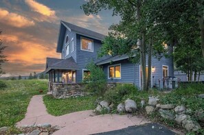 A two-story house with a stone foundation, a covered porch, and a pathway leading to the entrance. - Blue River Retreat - Private Hot Tub & Mtn Views (Blue River)