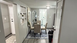 Un couloir comprenant un coin repas, une poubelle et un tapis rouge.