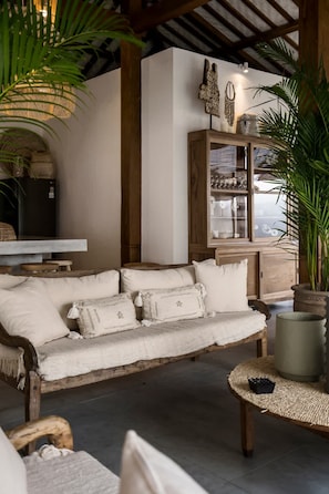 Ein gemütlicher Wohnbereich mit einem Holzsofa, einem gewebten Couchtisch und einer Vitrine mit Glastüren.
