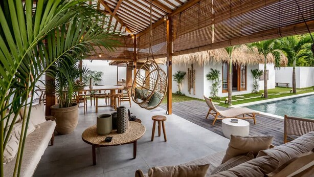 Un área de descanso al aire libre con piscina, mobiliario de madera, sillones colgantes y plantas en macetas.