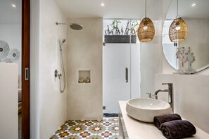 Ein modernes Badezimmer mit Dusche, großem Waschbecken und dekorativer Beleuchtung.