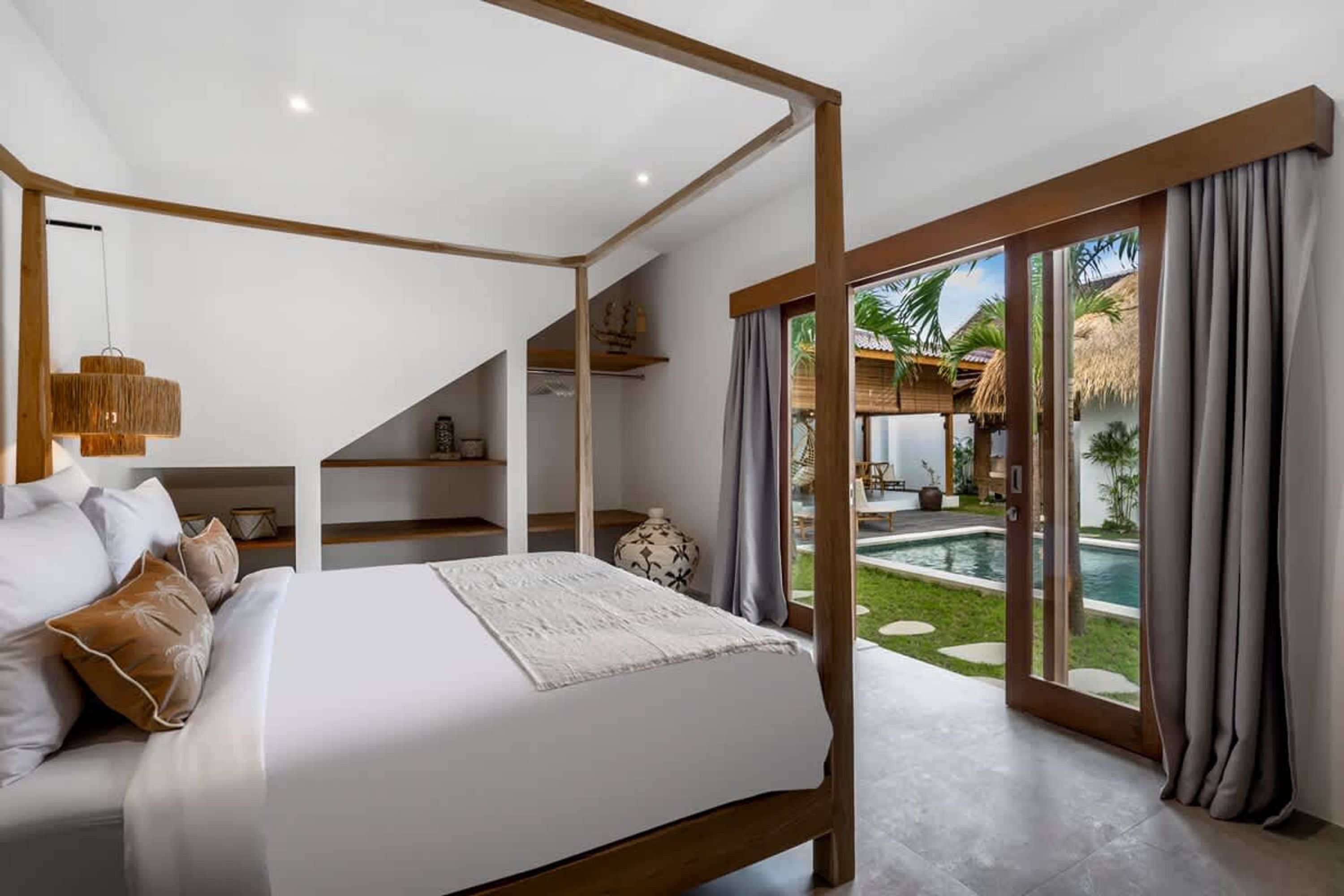 Un dormitorio con cama con dosel, vistas a una piscina y un balcón con cortinas.