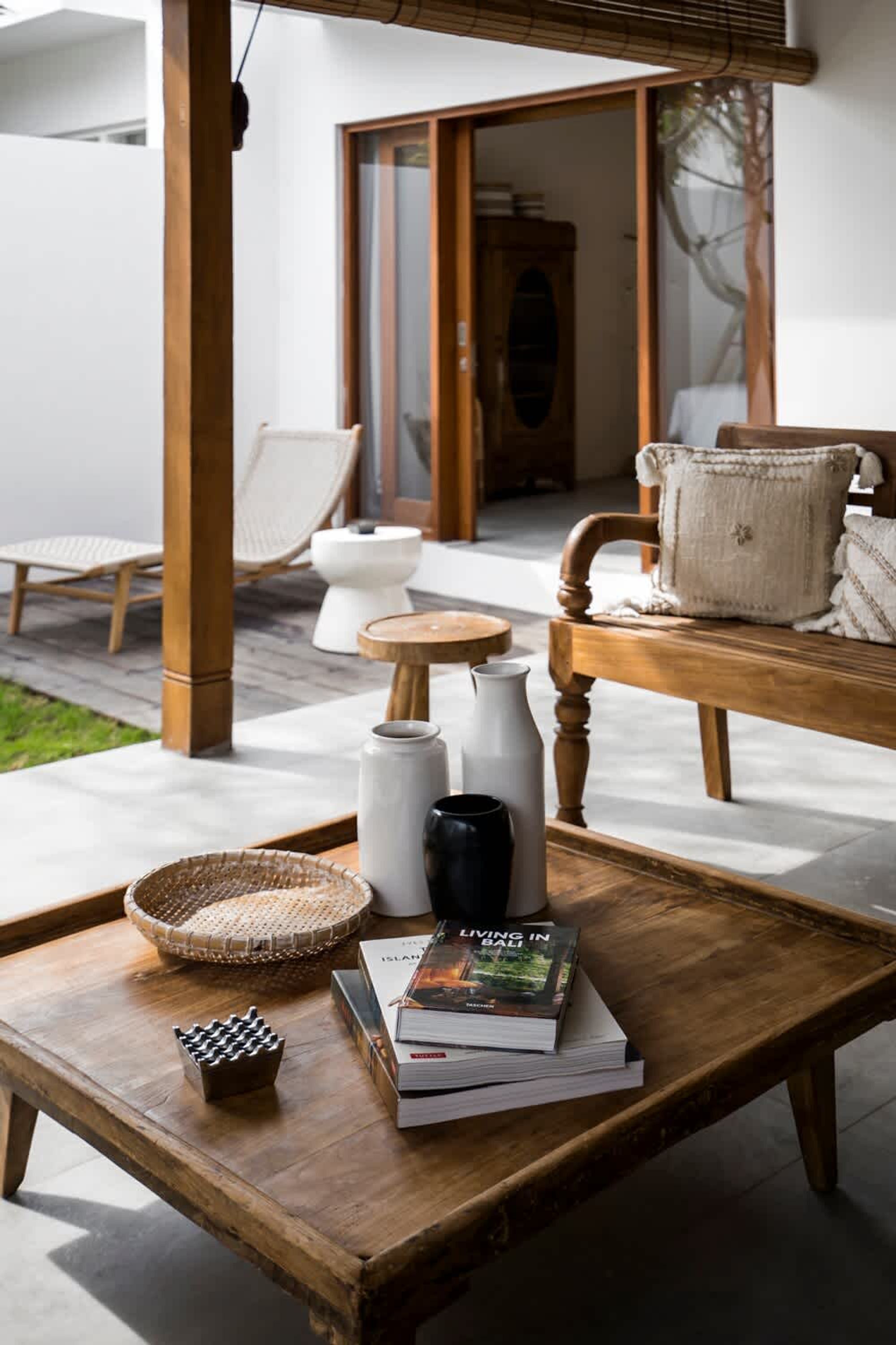 A wooden table with a tray, a book titled 'Living in Bali,' and a chess set.