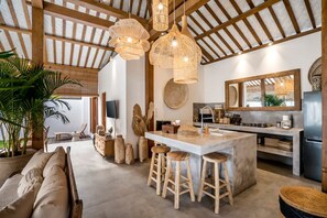 A spacious kitchen with a large island, wooden ceiling beams, and hanging wicker light fixtures. - Heaven 5 BR Pool Villa Seminyak Near the Beach (Dalung)