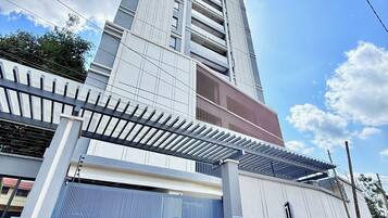 Un edificio alto con diseño moderno, una entrada vigilada y el nombre 'GEMLAND RESIDENCE' en la fachada.