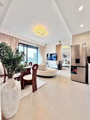Una sala de estar moderna con comedor, un ventanal grande y una cocina con refrigerador.