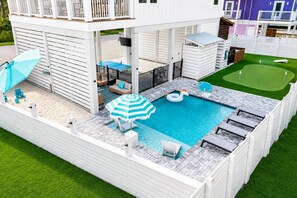 A pool area with a floating unicorn, lounge chairs, and a blue-striped umbrella. - Pool, Putting Green, Giant Sand Pit, Walk 2 Beach (Port St. Joe)