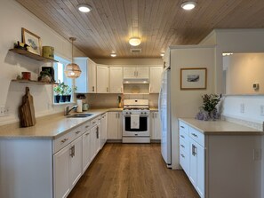A modern kitchen with white cabinetry, a wooden floor, and a central island.