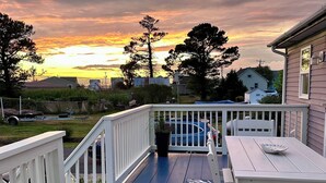 A deck with a railing, a table, and chairs. - Coastal Cottage Escape with Sunset Views, Near Beach, Bay & Wildlife Refuge (Chincoteague)